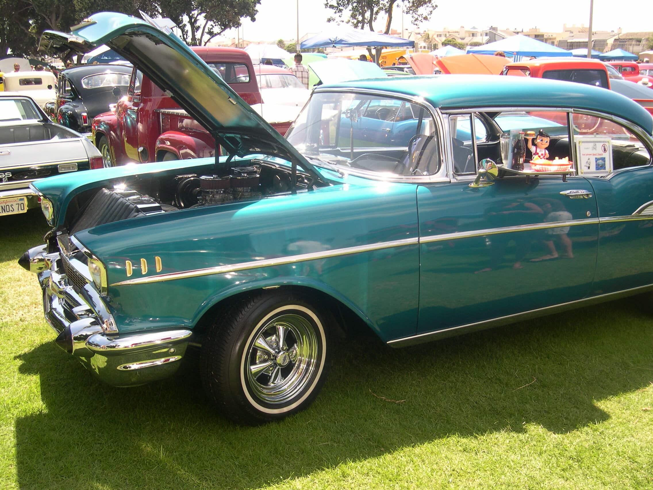 A candy-coated aquamarine/teal classic sports sedan from the 60s or 70s ; with chrome trim and whitewall tires