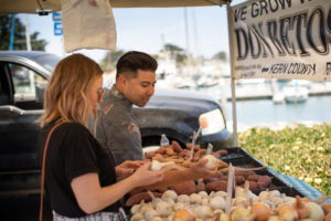 A vendor at CIH Farmers Market talks produce selection with a patron