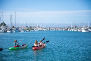 Smiling people paddling kayaks in Channel Islands Harbor