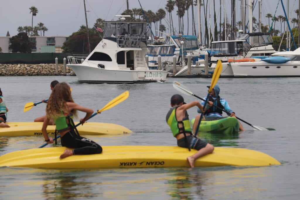 Kids kayaking and paddleboarding at Channel Islands Harbor during watersports camp.