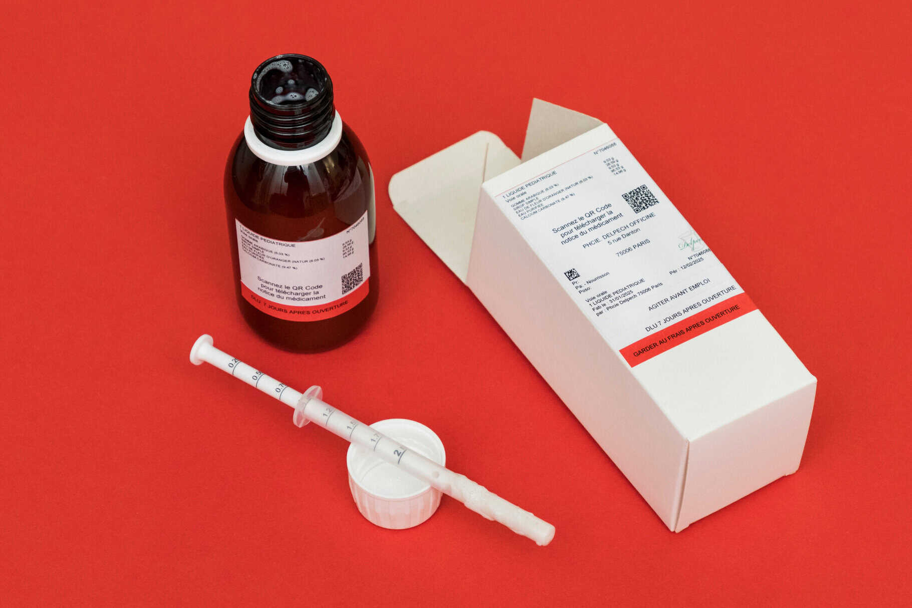 Flacon de médicament pédiatrique, seringue et boîte d'ordonnance sur fond rouge, concept de santé, pharmacie, traitement médical, injection, ordonnance sécurisée.