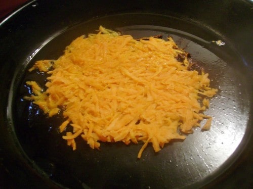 Image shows a frying pan of sweet potatoes being fried into hash browns.