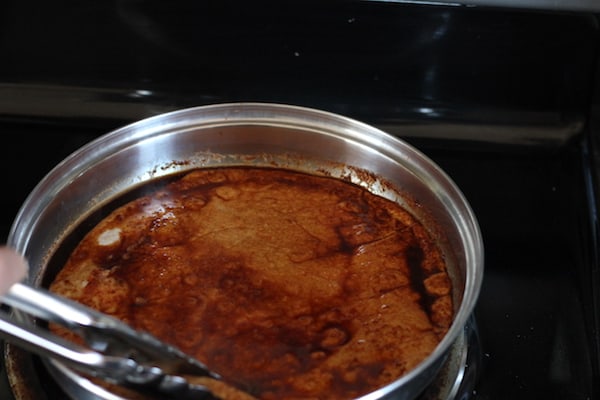 dipping tortillas in the chili bath for enchiladas