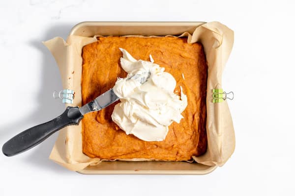 spreading cream cheese over gluten free pumpkin bars