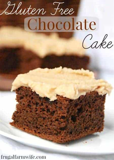 Image shows a close up of a piece of chocolate cate with creamy frosting. The rest of the cake is in the background, text above reads "Gluten Free Chocolate Cake"