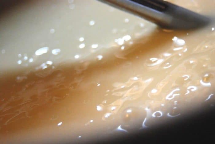 Image shows an immersion blender immersed in a soap mixture