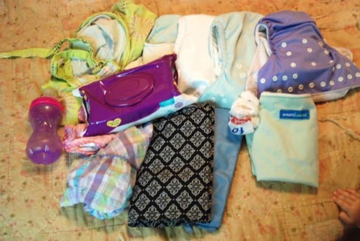 Photo shows a pile of clothes, wipes, and other items to keep in a diaper bag