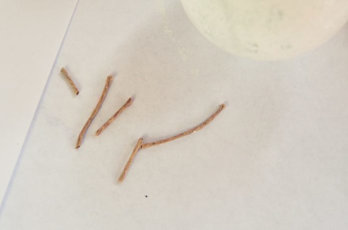 Image shows several small pieces of twine cut next to the glass ornament