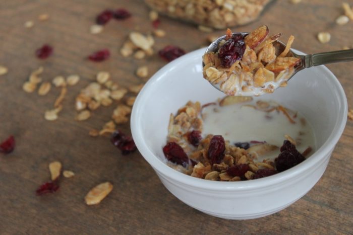 Photo shows a bowl of homemade granola with a spoon holding granola over it