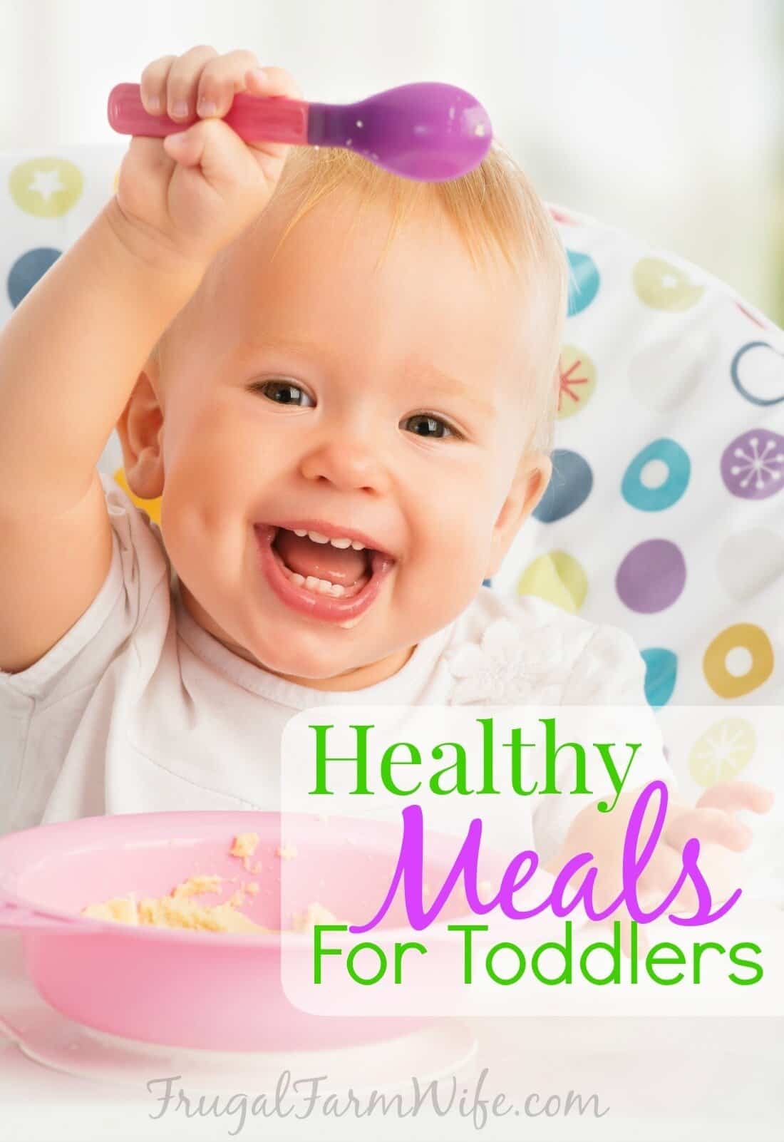 Image shows a toddler smiling in a high chair holding a spoon over their head. Text overlay reads "Healthy Meals For Toddlers"