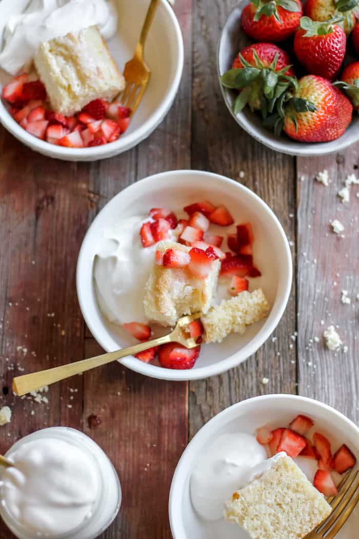 Photo shows several bowls of shortcake with strawberries and whipped cream on a table 