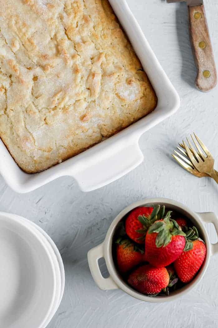 Photo shows a pan of shortcake next to a bowl of strawberries