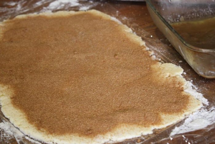 Photo shows the cinnamon roll dough rolled flat, and covered with cinnamon sugar