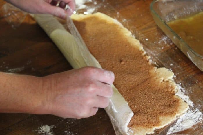 Photo shows hands rolling the cinnamon roll dough