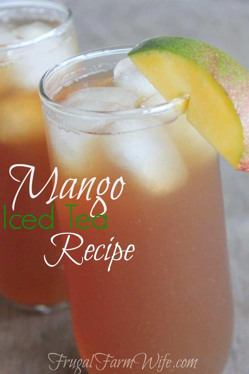 Image shows a close up of two glasses of iced tea, sitting on a table, with a mango garnishing the side of the glass. Text overlay reads "Mango Iced Tea Recipe"