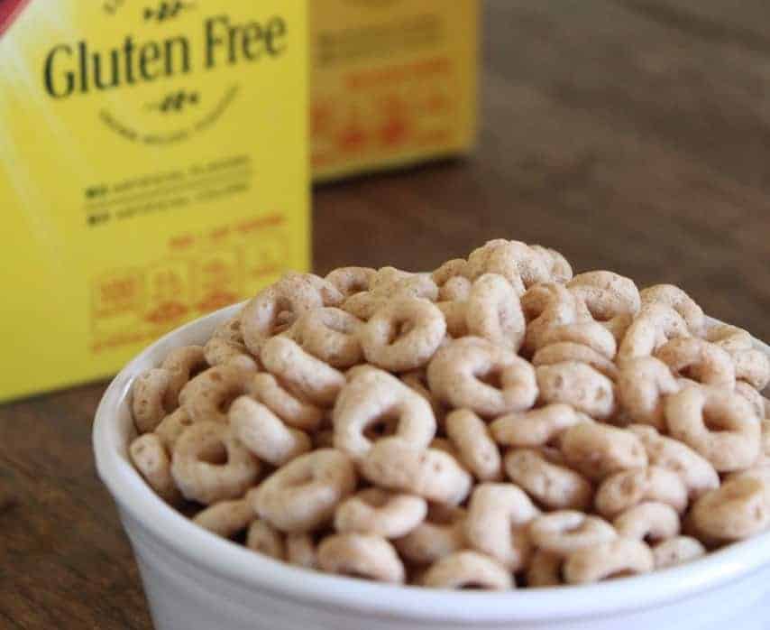 Image shows a close up of a large bowl of Cheerios with a box of cereal sitting behind it. 