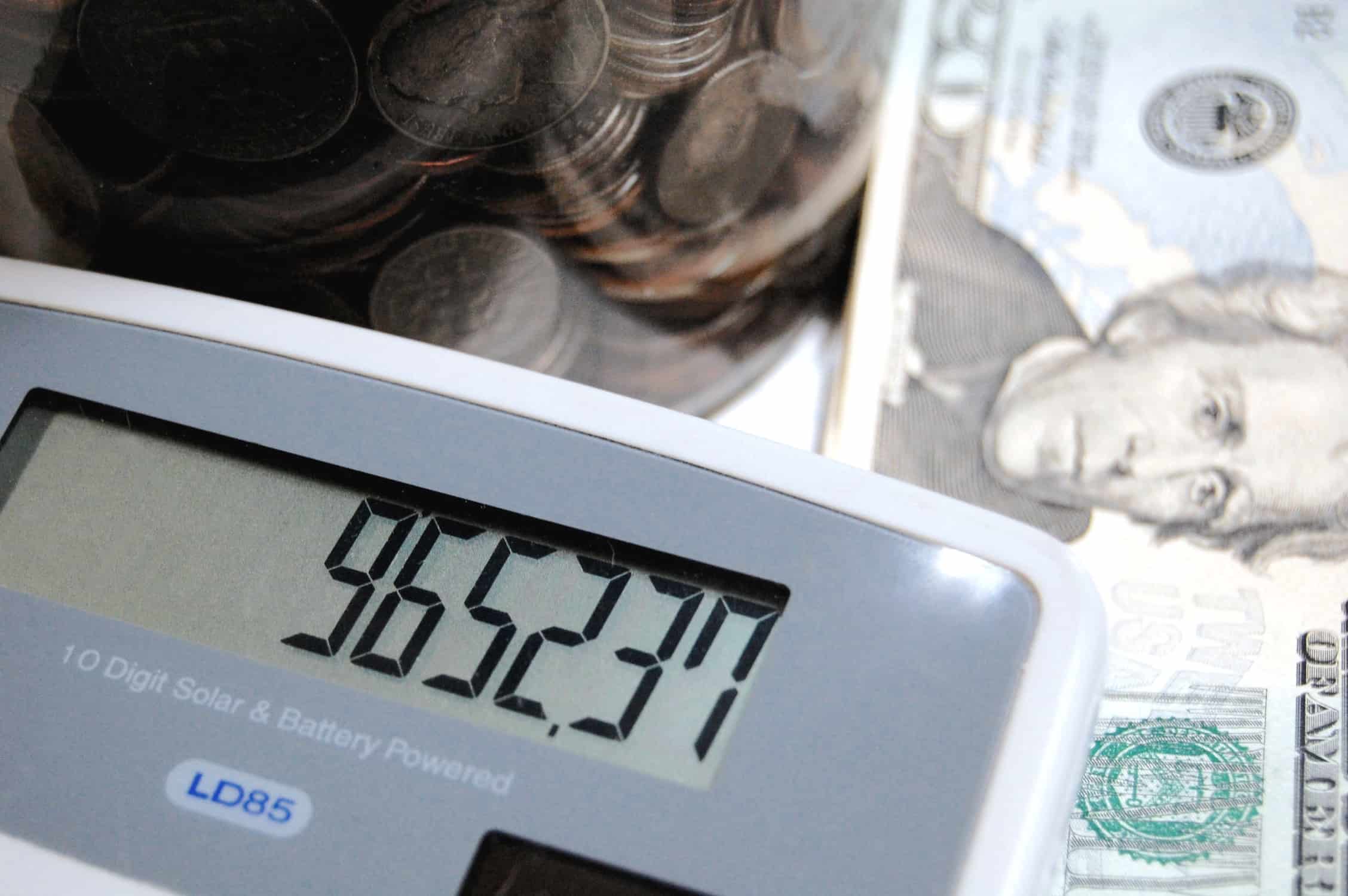 Image shows some money laid on a table with a calculator in the forefront