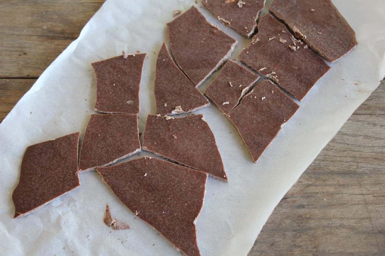 Image shows homemade skinny chocolate on parchment paper, broken into pieces.
