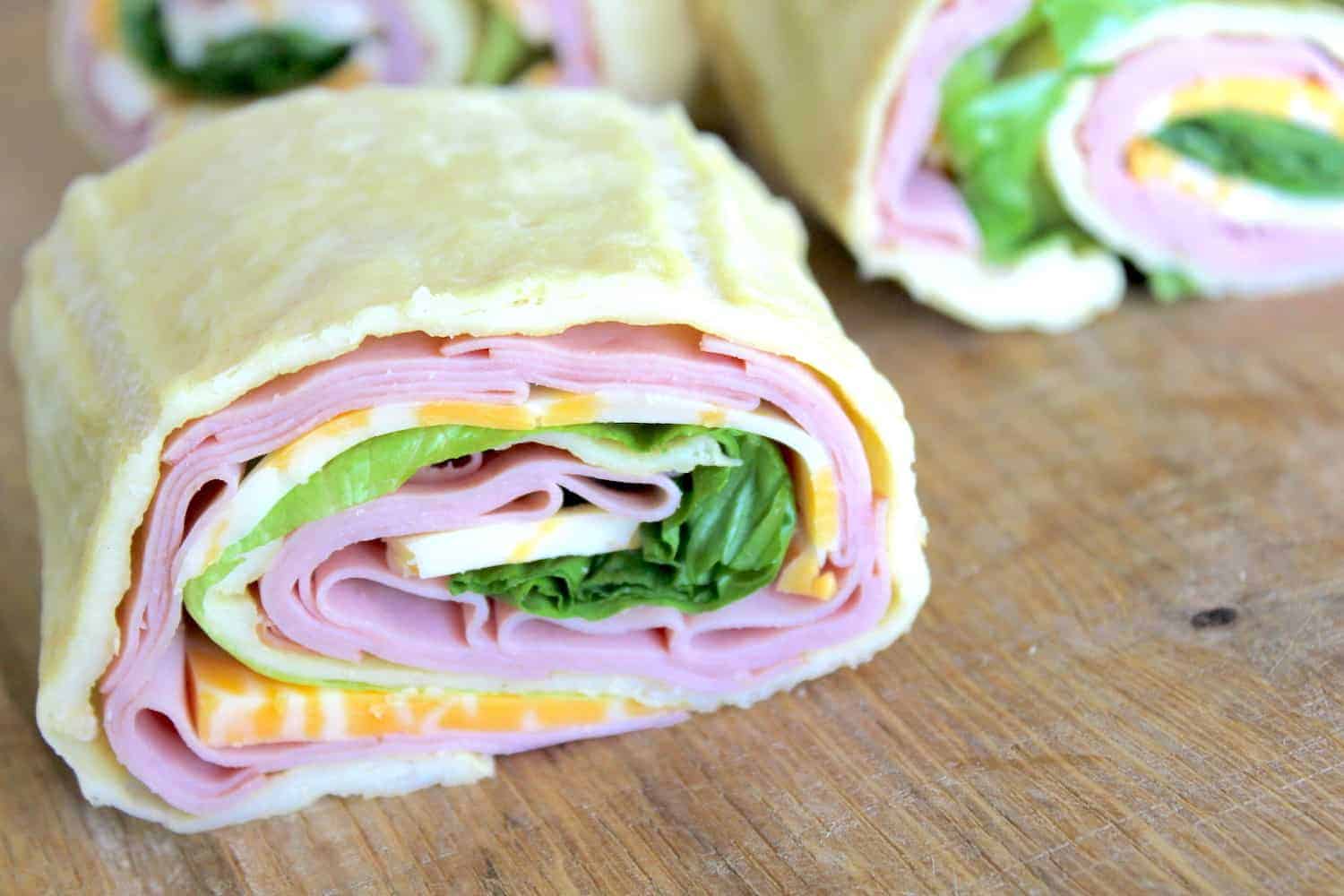 Image shows a close up of a gluten free sandwich wrap, cut into pieces, on a table.