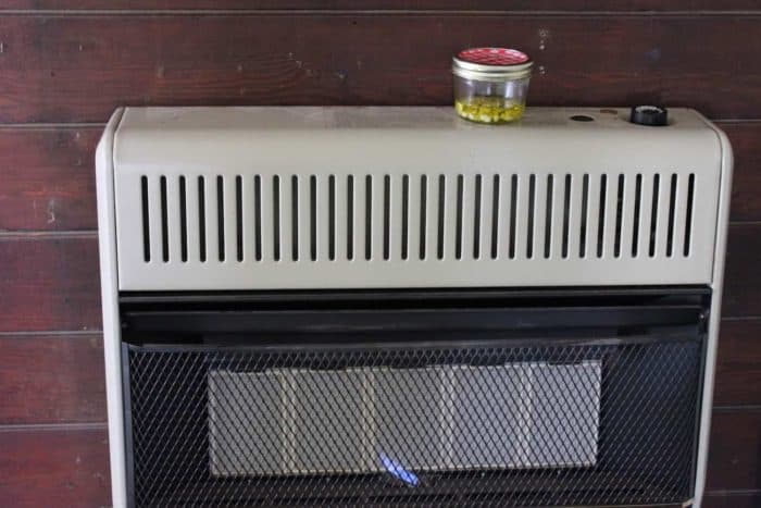 Photo shows a jar of garlic in oil on a heat register to warm 