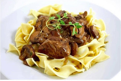 Steak Tips with mushroom gravy sits atop a pile of egg noodles