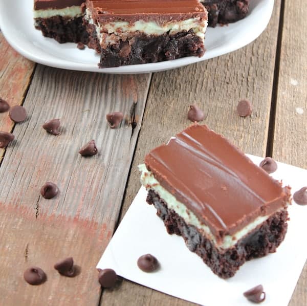 Photo shows several peppermint layer brownies on a table with chocolate chips