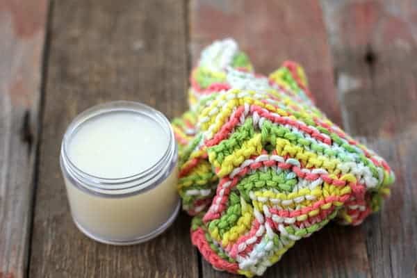 Photo shows a small jar of face wash next to a washcloth on a table