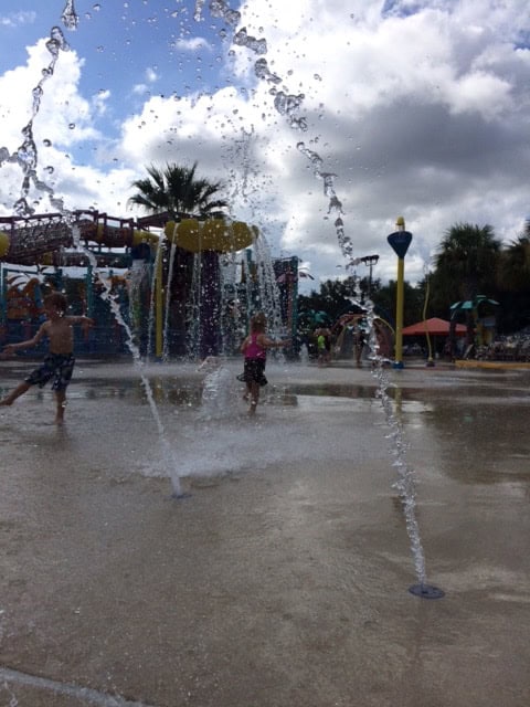 Image shows two small children playing in a splash pad