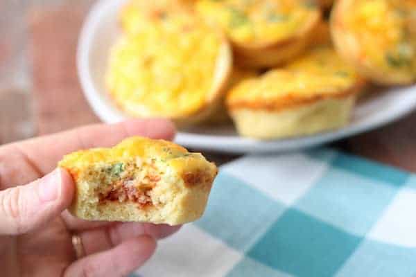 Image shows a hand holding a mini, egg, breakfast pizza