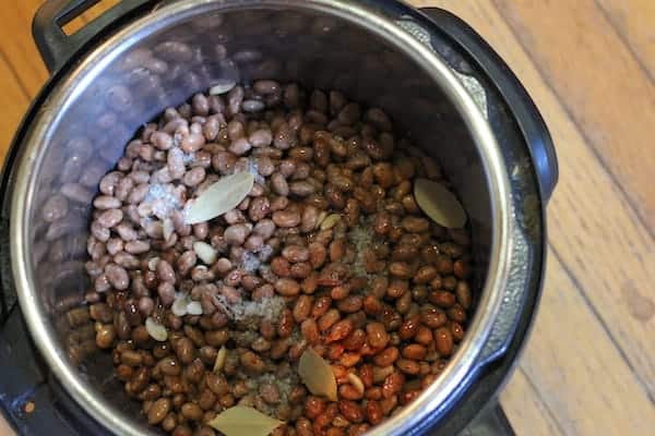 Image, taken from above, shows beans and seasoning in an Instant Pot ready to be cooked.