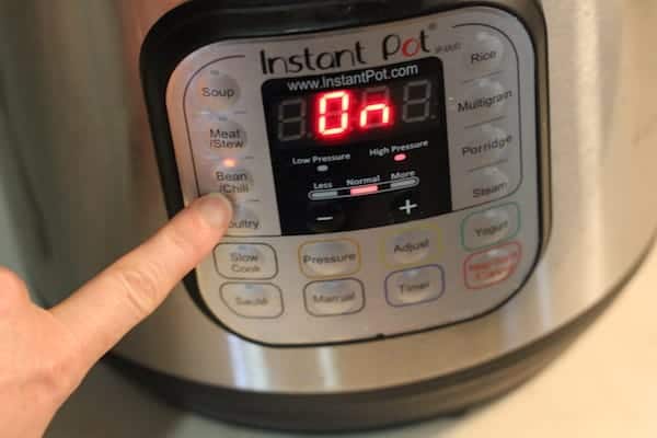 Image shows a finger turning on an Instant Pot to cook the beans
