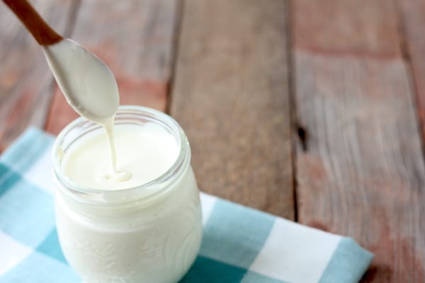 Image shows a wooden spoon over a jar of sweetened condensed milk