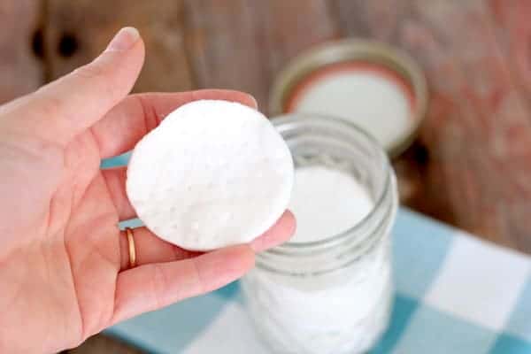 Image shows a hand holding a round pad over a jar on a table