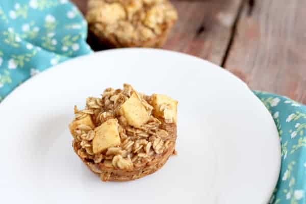 Image shows a baked oatmeal cup on a white plate with a turquoise printed towel under it.