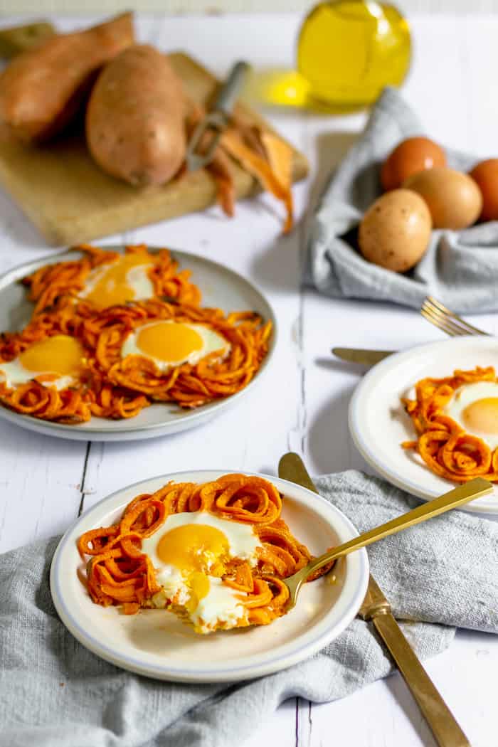Photo shows several plates of sweet potatoes with eggs, with potatoes in the background 