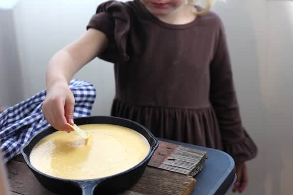 Image shows a young girl dipping a chip into cheese sauce on a table