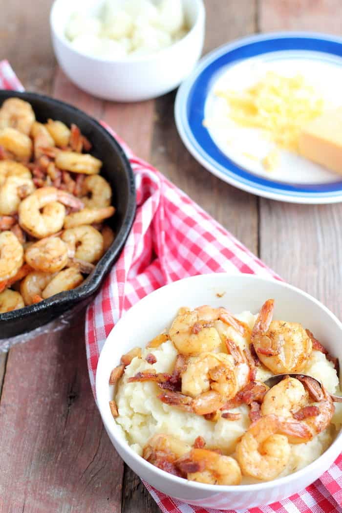 Image shows several bowls of shrimp and grits on a table 