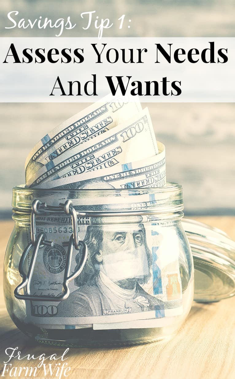 Image shows a glass jar on a desk with several $100 bills coming out of it. Text above reads "Savings Tip !: Assess Your Needs and Wants"