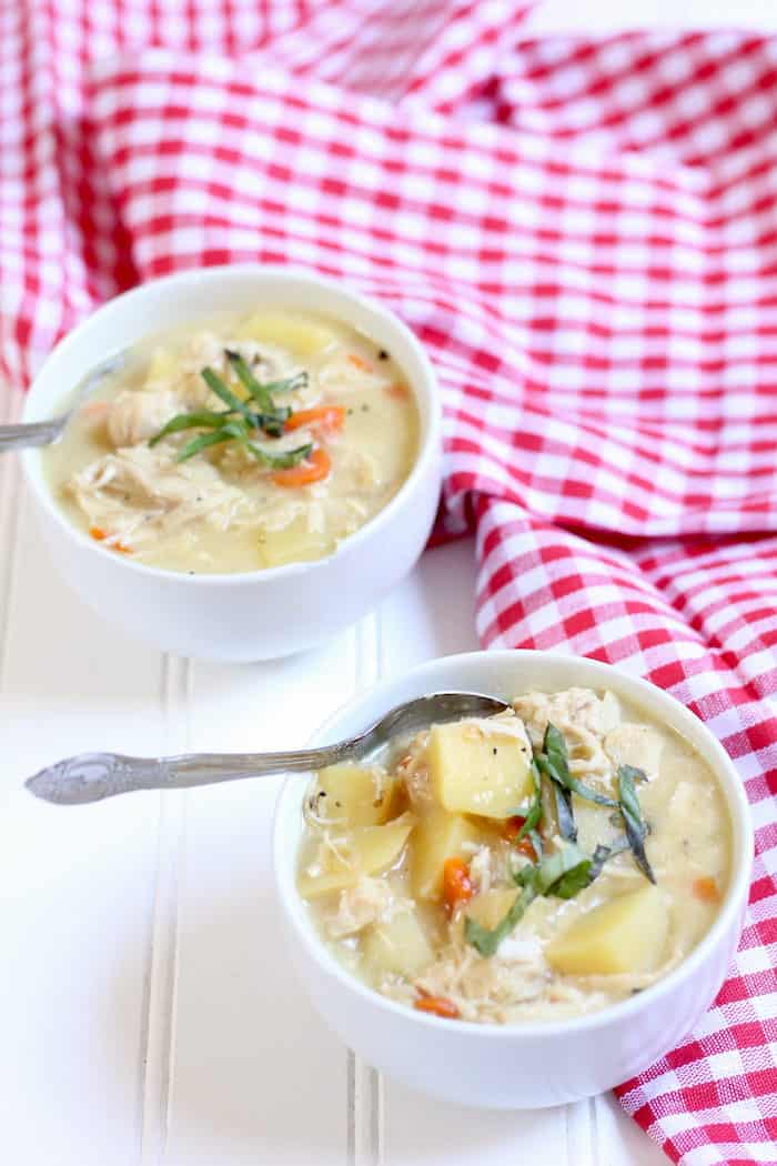 Photo shows two bowls of chicken soup on a table with a red and white tablecloth