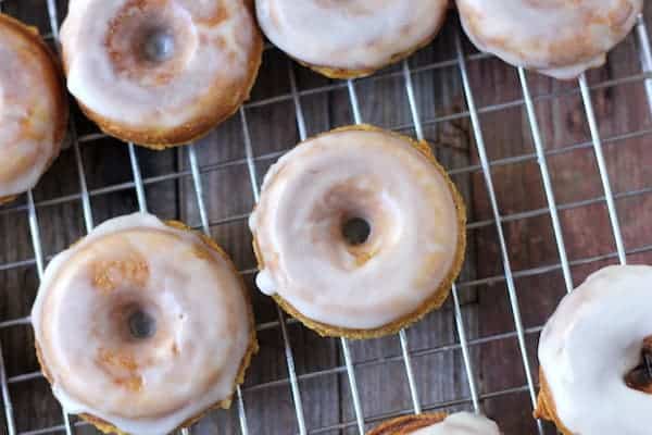 Image, taken from above, shows pumpkin donuts on a rack with icing