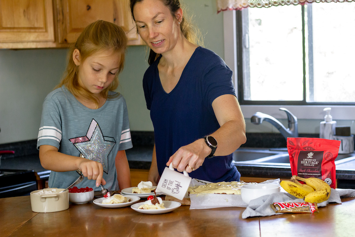 Image shows a woman and young girl serving cake in a kitchen