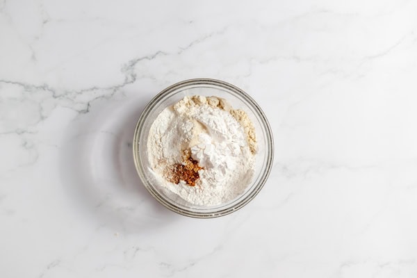 Image shows a glass bowl full of gluten free dry ingredients for pumpkin cookies