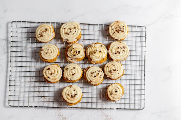 Image, taken from above shows gluten free pumpkin cookies topped with cacao nibs on a cooling rack