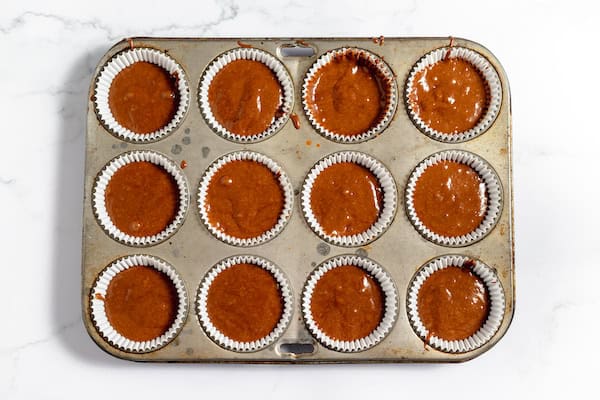 Image, taken from above, shows gluten free chocolate cupcakes in muffin tin ready to bake