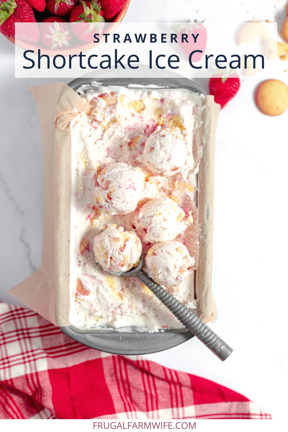 Image, taken from above, shows a small pan with strawberry shortcake no-churn ice cream in it. An ice cream scoop rests on top along with several scoops.