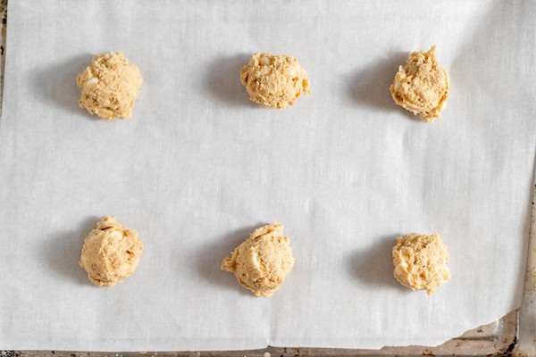 Image, taken from above shows cookie dough rolled into balls ready to bake on a cookie sheet.