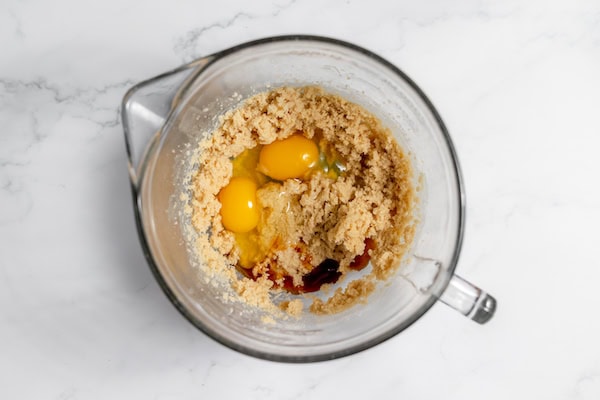 eggs and vanilla in a bowl with beaten butter and sugar
