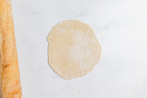 Image shows raw tortilla rolled out on table ready to cook