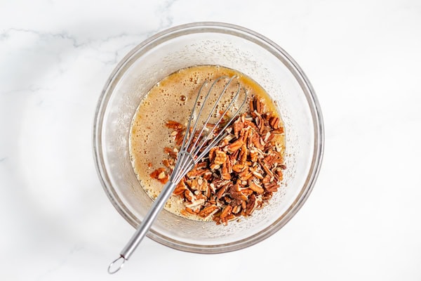 Image, taken from above, shows a whisk mixing the filling for the pecan bars