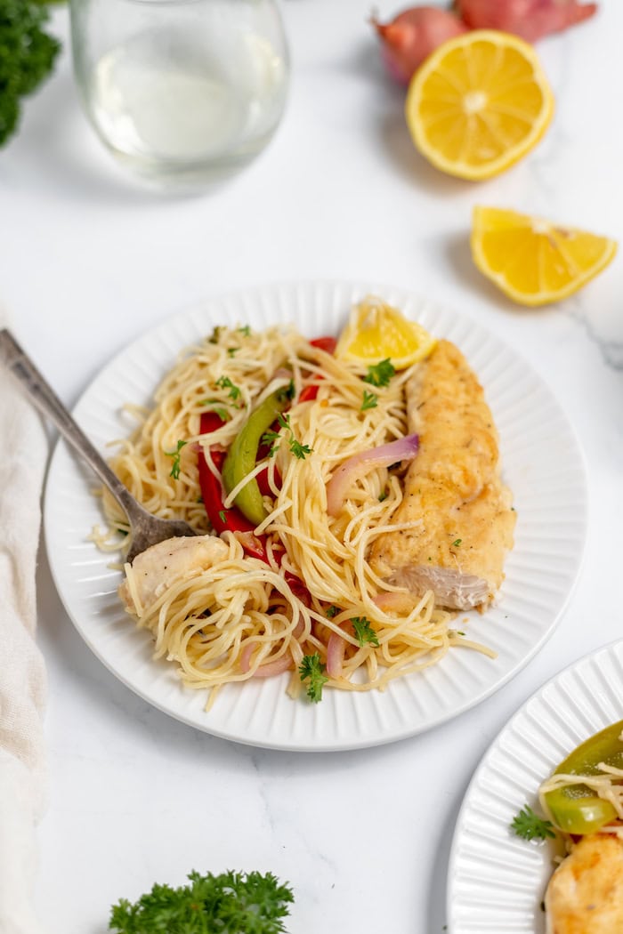 Image shows a plate with a serving of chicken scampi with vegetables and a fork in the plate. 